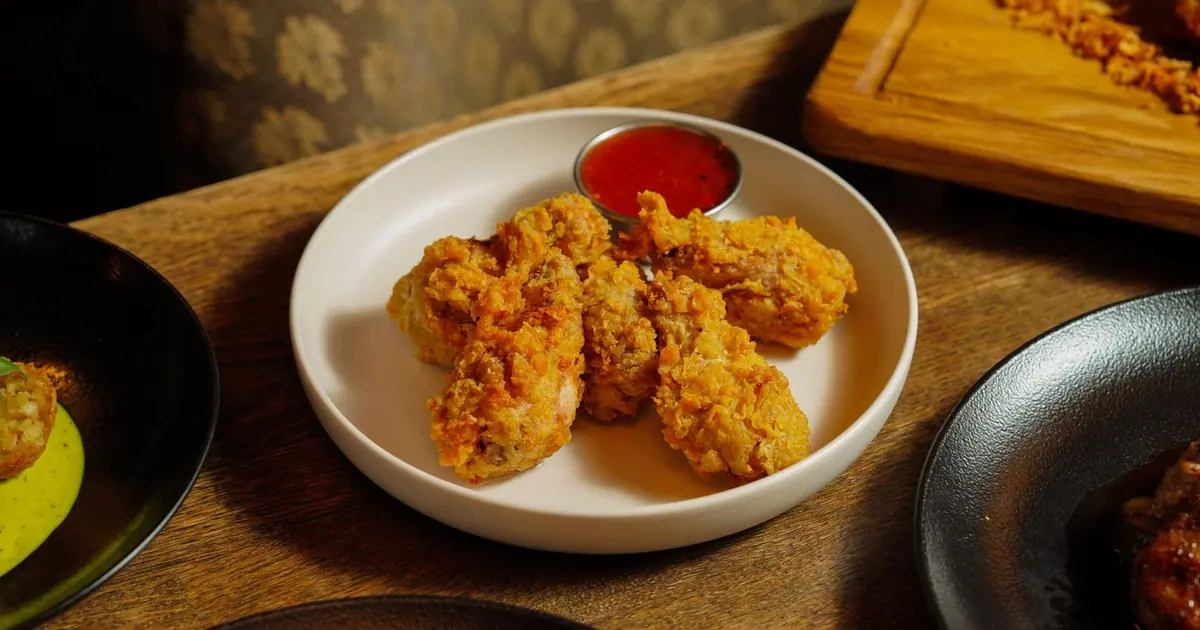 Fried chicken wings on a plate with a red dipping sauce - The best Wingstop flavors: our picks for every taste