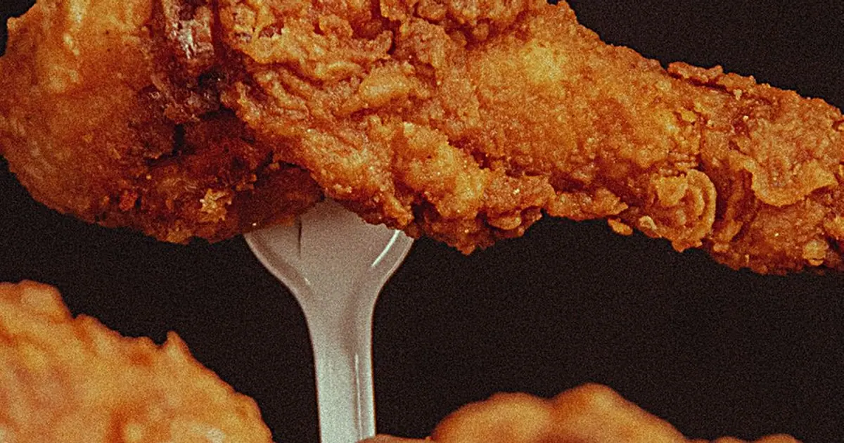 A fried chicken drumstick on a fork - How to reheat Wingstop wings (and store leftovers)