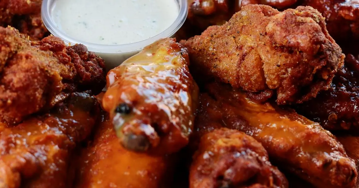 Close-up of saucy chicken wings with a creamy dip - Spicy Wingstop flavors, ranked from mild to Atomic
