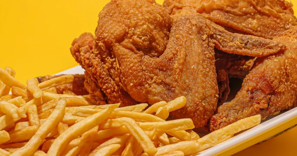 Fried chicken wings and fries on a yellow background - Wingstop cost per wing: what each wing really costs