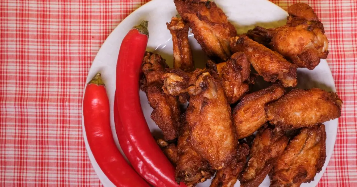 Chicken wings garnished with hot chili peppers - Wingstop flavors by heat level, from no heat to extra hot