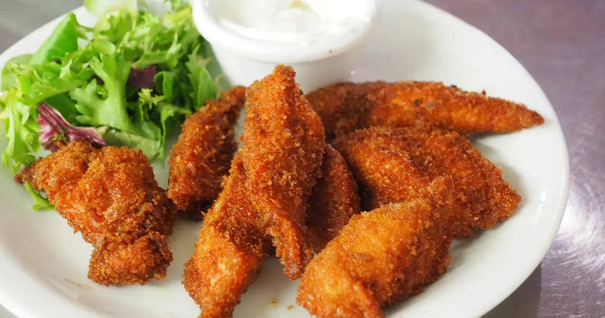Breaded chicken tenders on a plate with a dip - Wingstop for kids and picky eaters